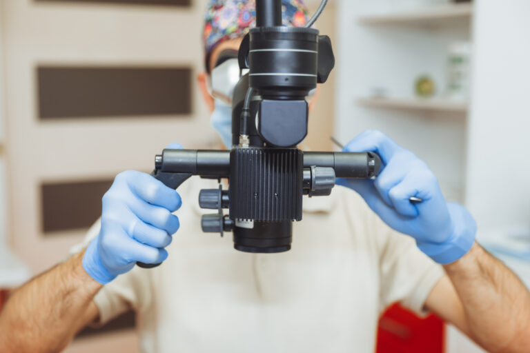 Arzt mit Mikroskop und Handschuhen